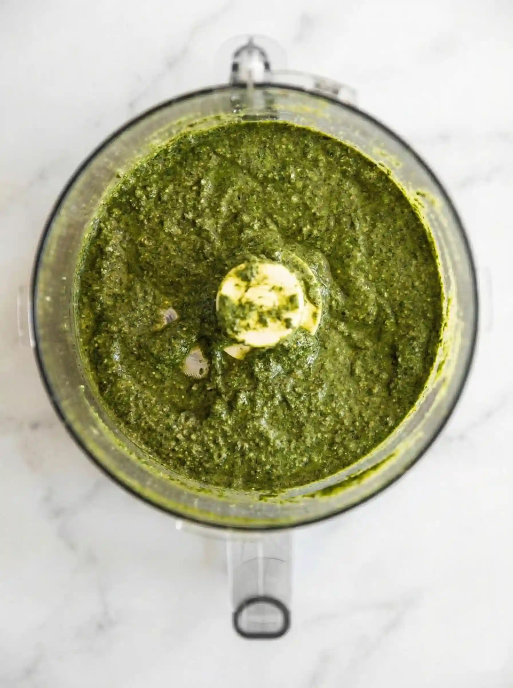 Basil pesto ingredients in a food processor before blending for pesto pasta salad