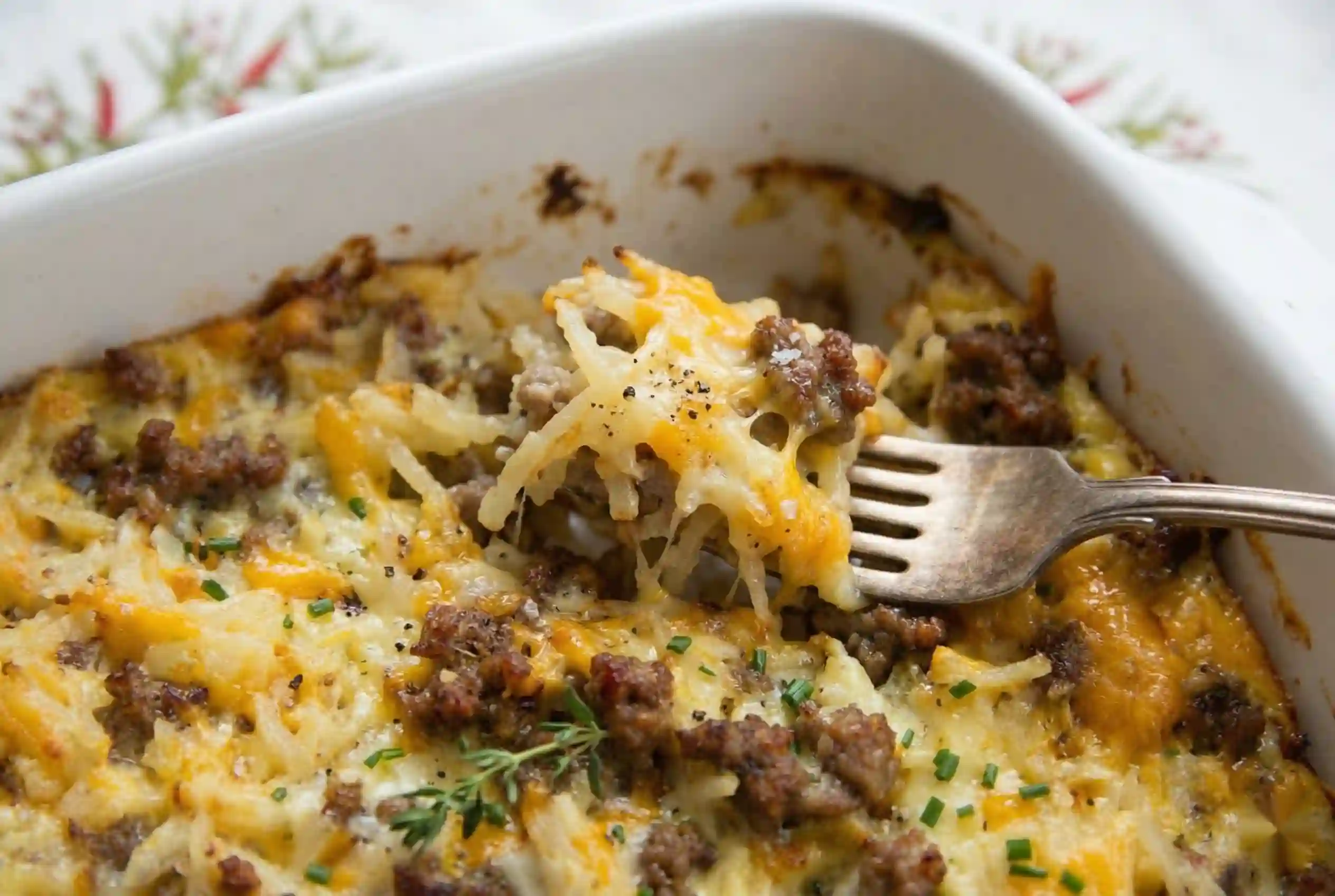 Close-up slice showing cheese pull, sausage chunks, and hash brown layers in breakfast casserole.