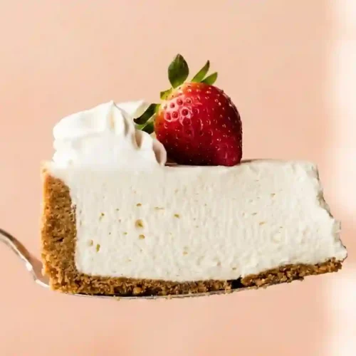 Final no bake cheesecake on a serving plate with strawberry topping