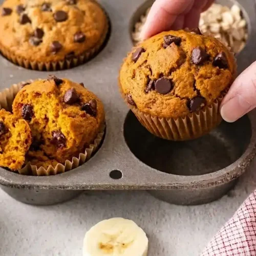 Freshly baked oat flour banana muffins with chocolate chips in a rustic muffin tin for Mixo Recipes.