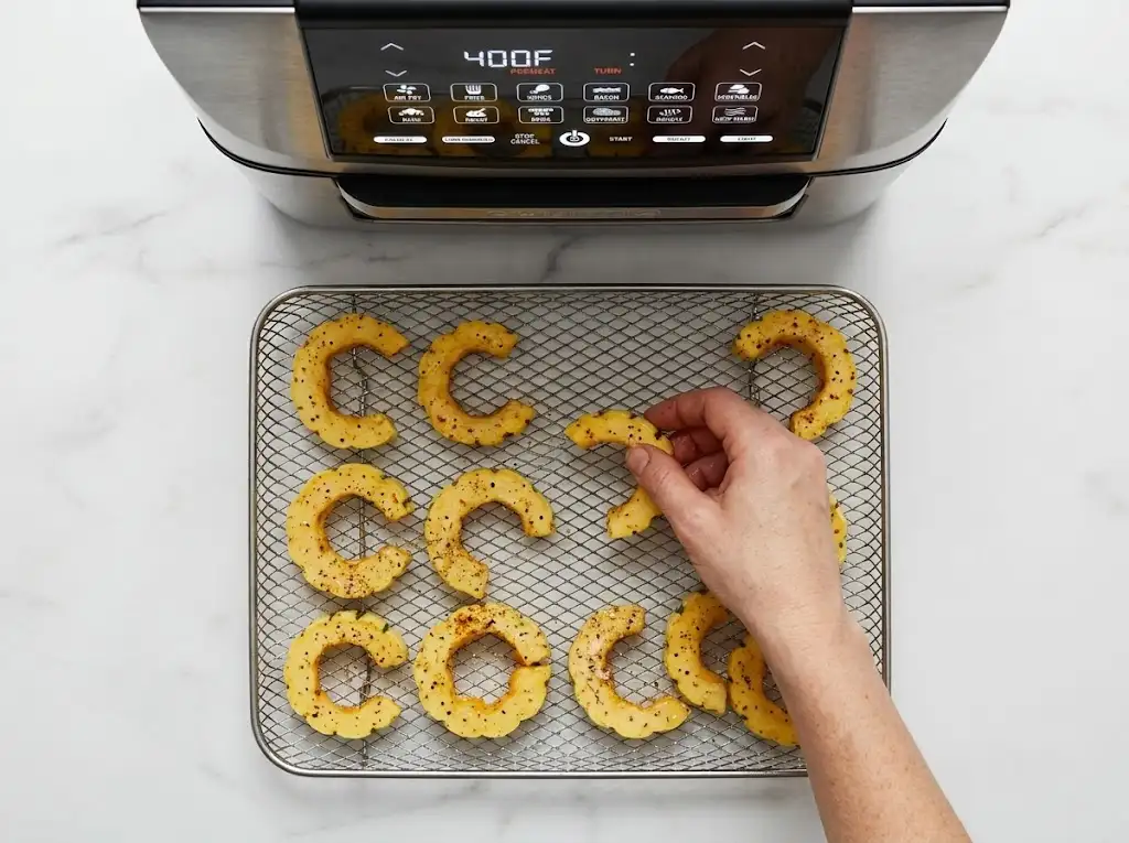 step3 Air Fryer Delicata Squash Arranging seasoned delicata squash slices in a single layer on an air fryer basket.
